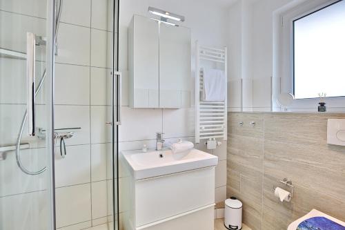 y baño blanco con lavabo y ducha. en Ferienhaus Brandt Ferienhaus Brandt Appartement 3 Möwenkieker, en Haffkrug