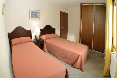 two beds in a hotel room with orange sheets at Edificio Reyes in La Adrada