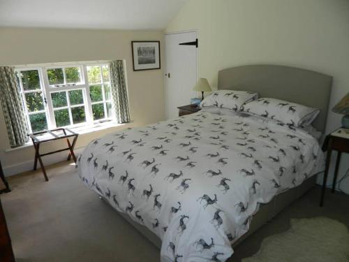a bedroom with a bed with a comforter with birds on it at River Cottage a country retreat in wooded gardens in East Stoke