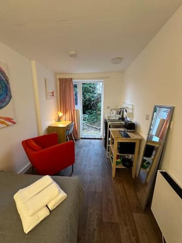 Zimmer mit einem Bett, einem Schreibtisch und einem roten Stuhl in der Unterkunft Garden Apartment with free Parking and EV in Bristol