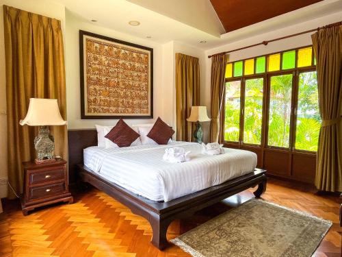 um quarto com uma grande cama branca e janelas em Baleeyan Residence em Thalang