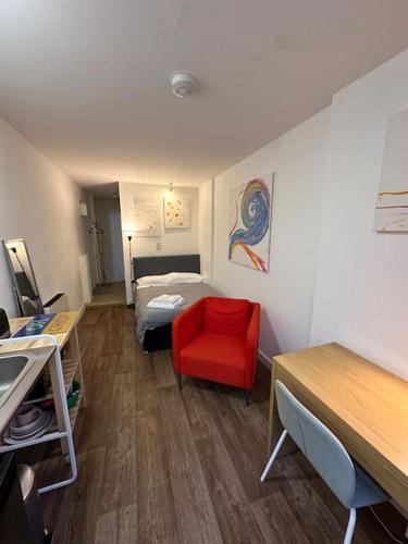 ein kleines Zimmer mit einem Bett und einem roten Stuhl in der Unterkunft Garden Apartment with free Parking and EV in Bristol