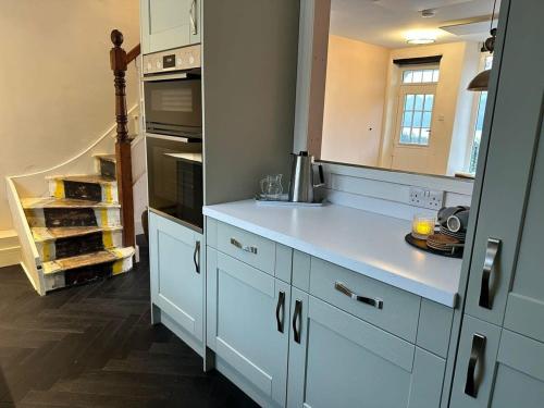 a kitchen with white cabinets and a counter top at Waterside Victorian house at Golant Fowey in Fowey