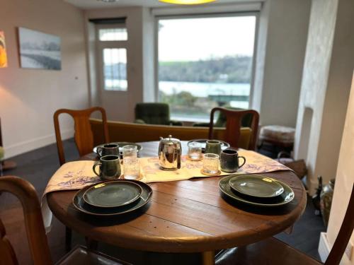 a wooden table with plates and glasses on it at Waterside Victorian house at Golant Fowey in Fowey