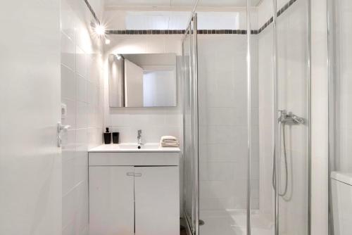 La salle de bains blanche est pourvue d'un lavabo et d'une douche. dans l'établissement Quinta de Loubite - Jacarandá, à Lagoa