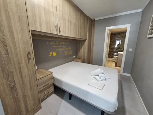 um pequeno quarto com uma cama branca e armários de madeira em Apartamento Florida Beach em Benidorm