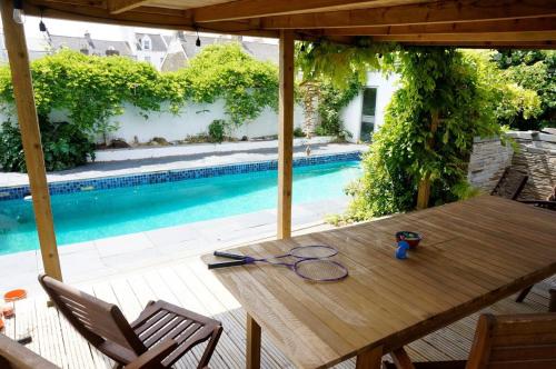 una mesa de madera en un patio con piscina en Spacious Town House with Swimming Pool, en Plymouth