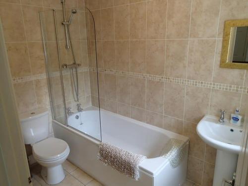 een badkamer met een bad, een toilet en een wastafel bij Cosy home in an area of outstanding natural beauty in Wookey Hole