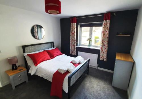 Schlafzimmer mit einem Bett mit roten Kissen und einem Fenster in der Unterkunft The Mariners' Beacon Torquay in Torquay