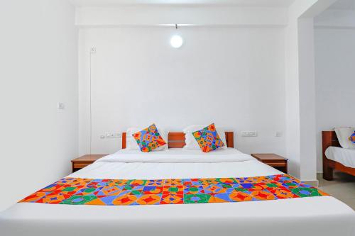 a large white bed with a colorful blanket on it at FabHotel Raj Residency Madikeri in Madikeri