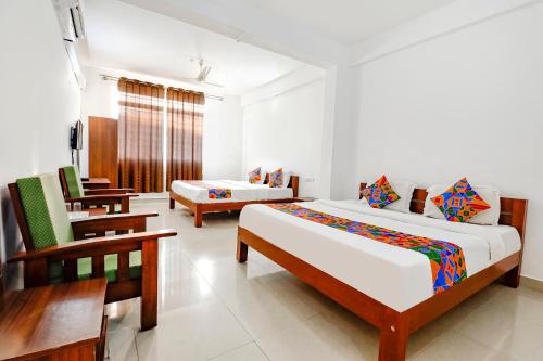 a bedroom with two beds and a table and chairs at FabHotel Raj Residency Madikeri in Madikeri