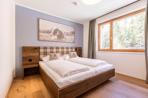 1 dormitorio con 1 cama grande en una habitación con ventana en Almresort Sonnenalpe Nassfeld by ALPS RESORTS en Sonnenalpe Nassfeld