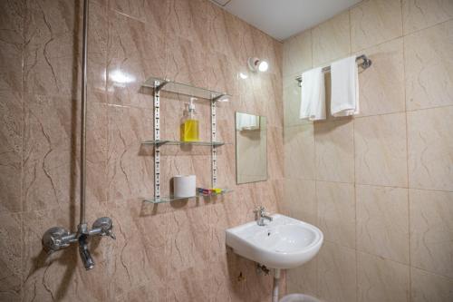 a bathroom with a sink and a toilet and a mirror at Guesture Stays - Dwellington, Electronics City Phase 2 in Bangalore