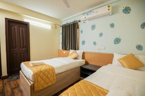 a hotel room with two beds and a window at Guesture Stays - Dwellington, Electronics City Phase 2 in Bangalore