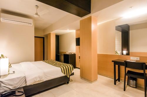 a bedroom with a bed and a desk and a table at Super Capital O Hotel Konar Inn in Turambhe
