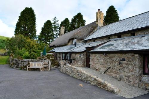 an old stone building with a bench in front of it at Idyllic Dartmoor Cottage in Postbridge