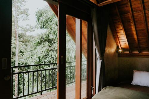 a room with a balcony with a bed and a window at Country side room northern UBUD in Tegalalang