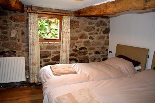 um quarto com uma cama e uma parede de pedra em Idyllic Dartmoor Cottage em Postbridge