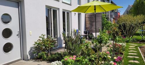 a patio with a yellow umbrella in a garden at Ferienwohnung Gartenblick mit Terrasse in Bad Abbach
