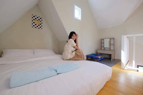a woman sitting on a bed in a room at The iNow ไอหนาว เขาค้อ in Khao Kho