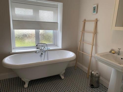 a white bath tub in a bathroom with a window at Stunning Victorian Dartmoor House in Yelverton