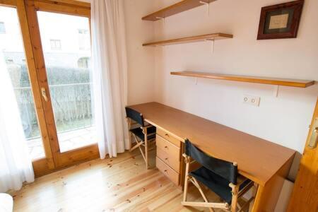 a room with a desk with two chairs and a window at Casa amb jardí Alp in Alp