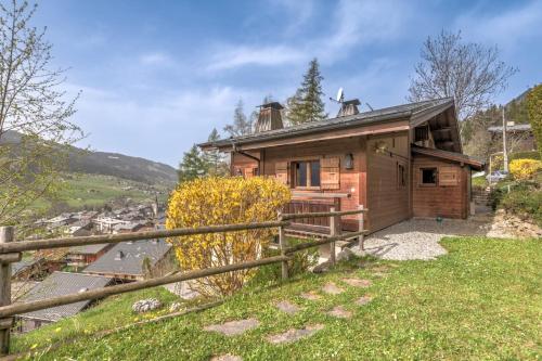 a wooden house on a hill with a fence at Chalet Les Cimes - Welkeys in Praz-sur-Arly