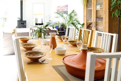 - une table en bois avec des bols et des verres à vin dans l'établissement Maison récente proche centre-ville, les Sables 8 personnes, à Les Sables-dʼOlonne