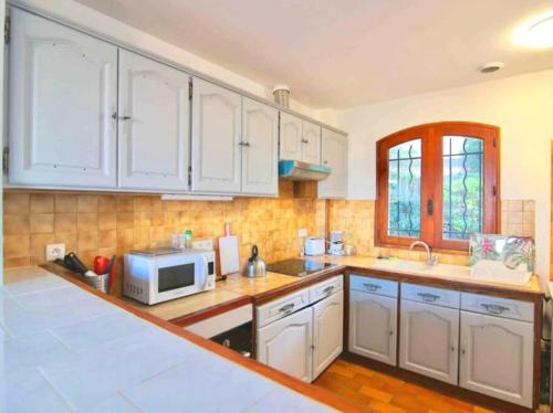 une cuisine avec des armoires blanches et un micro-ondes dans l'établissement Haut de Villa vue mer dégagée-T3, à La Seyne-sur-Mer
