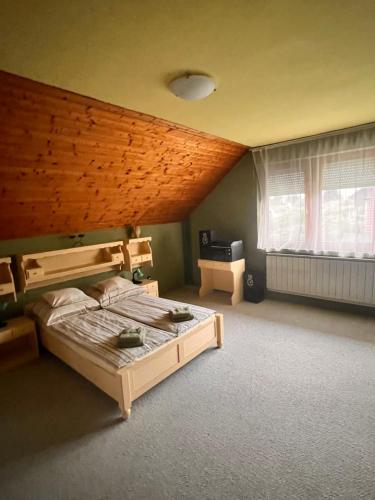 a bedroom with a bed and a wooden ceiling at Juhász Apartman in Gyenesdiás