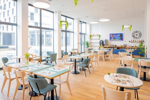 uma cafetaria com mesas, cadeiras e janelas em All Suites Appart Hotel Le Havre em Le Havre