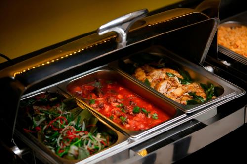 ein Buffet mit drei Tabletts mit Speisen und Gemüse in der Unterkunft Hanoi Harmonia Hotel & Spa in Hanoi