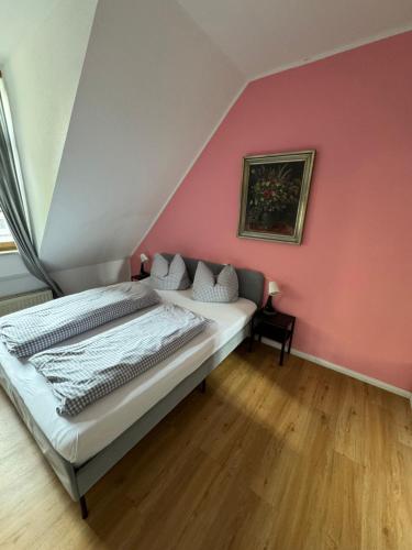a bedroom with a bed and a pink wall at Gasthaus Fischerrosl in Münsing am Starnberger See