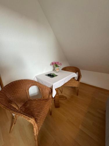 a table with two chairs and a vase with flowers on it at Gasthaus Fischerrosl in Münsing am Starnberger See