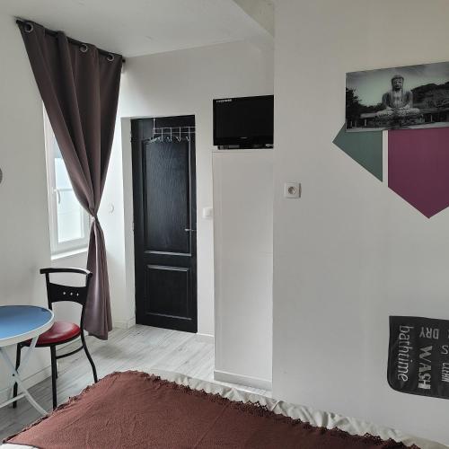 Habitación con puerta negra, mesa y silla en Chambre pour 2 personnes à Formigny RDC, en Formigny