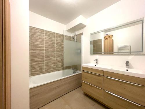 une salle de bain avec une baignoire, un lavabo et un miroir dans l'établissement La Terracotta Paris 8 min, à Bagneux