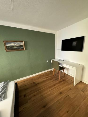 a room with a desk and a tv on a wall at Gasthaus Fischerrosl in Münsing am Starnberger See