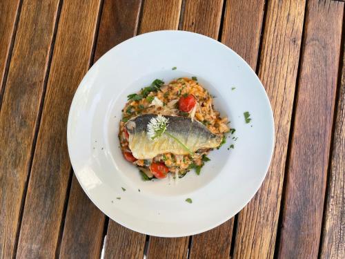 a white plate of food with fish on rice at Gasthaus Fischerrosl in Münsing am Starnberger See