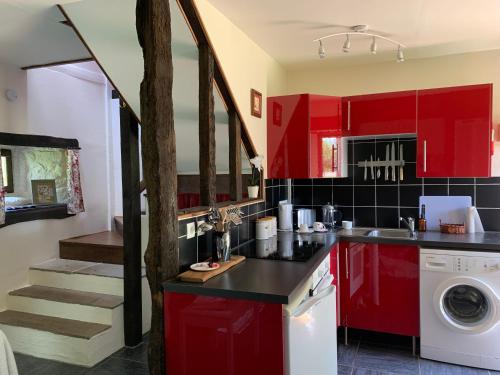 une cuisine rouge avec des placards rouges et un escalier dans l'établissement Charming 1-Bed Cottage in Ceauce, à Céaucé