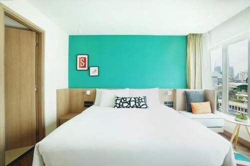 a bedroom with a large white bed and a blue wall at SQ Boutique Hotel in Bangkok