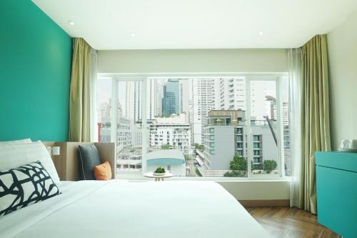 a bedroom with a large window with a view of a city at SQ Boutique Hotel Managed by The Ascott Limited in Bangkok