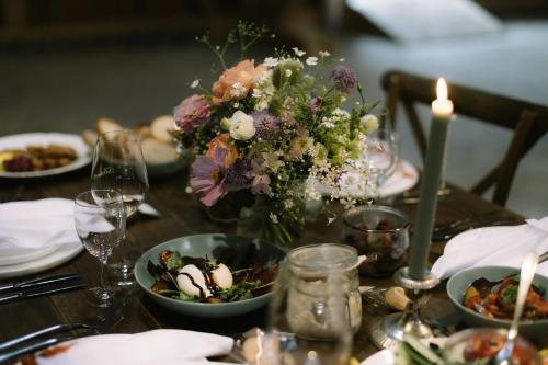 a table with a vase of flowers and plates of food at Gasthaus Fischerrosl in Münsing am Starnberger See
