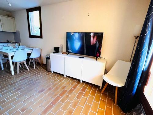 a living room with a tv and a table and chairs at Charmant 2 p proche activité in Saint-Martin-Vésubie