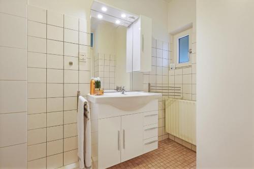 La salle de bains blanche est pourvue d'un lavabo et d'un miroir. dans l'établissement Holiday home Haringvliet 11 - Noordzeepark Ouddorp, garden, terrace, carport, near the beach and dunes - not for companies, à Ouddorp