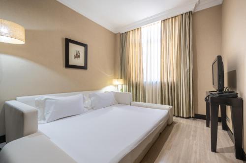 a hotel room with a white bed and a television at Hotel Saray in Granada
