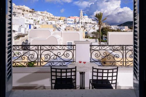 a table and chairs on a balcony with a view of a city at Ikio Concept Santorini in Pyrgos