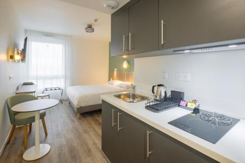uma cozinha com um lavatório e um quarto com uma cama em All Suites Appart Hotel Le Havre em Le Havre