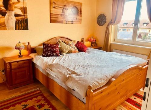 um quarto com uma cama de madeira com almofadas e uma janela em Bijoux am Dreiländereck! em Weil am Rhein