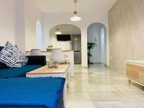a living room with a blue couch and a kitchen at Playa Wabi Fuengirola in Fuengirola