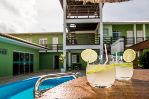 two drinks sitting on a table next to a pool at Pousada Mar Do Leste in Florianópolis